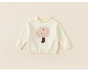 Close-up of cream knit sweater showing pink mushroom jacquard pattern and ribbed cuffs