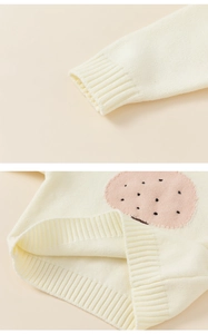 Detail of ribbed cuffs and hem on cream knit sweater with pink polka dot patch