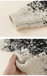Close-up of soft black and white knit fabric showing thick plush texture and cuff details