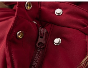 Detail of red children's winter coat featuring resin zipper and metal snap buttons