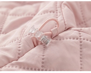 Detail of pink quilted coat showing adjustable drawstring with transparent plastic cord lock