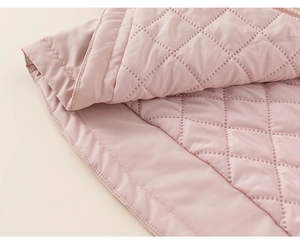 Detail of pink quilted diamond pattern fabric with soft stitching for girls' winter jacket