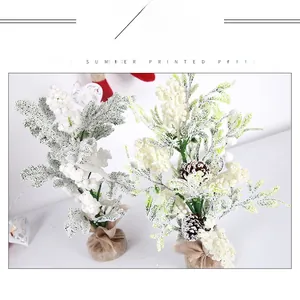 Detail of mini snow-flocked Christmas tree with pine cones and linen-wrapped base
