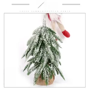Detail of mini frosted Christmas tree with snow-flocked needles and burlap base