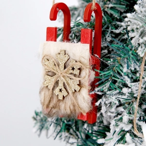 Traîneau de Noël rouge en bois avec fourrure et flocon doré sur une branche de sapin