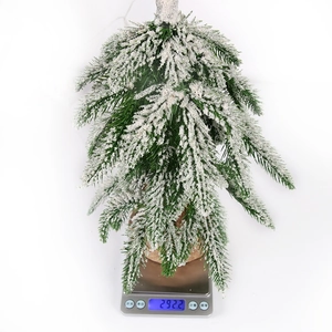 Miniature snow-flocked Christmas tree on scale showing the weight of 292.2 grams
