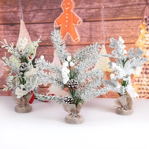 Miniature snow-flocked Christmas trees with pinecones and berries for tabletop decor