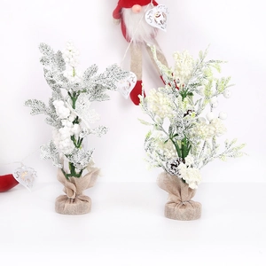 Miniature snow-covered Christmas tree with white berries and rustic burlap base