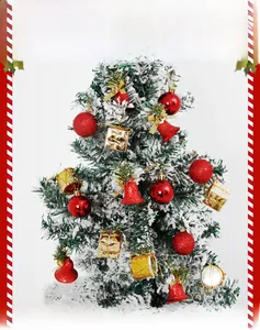 Close-up of red glitter balls, golden bells, and mini gift boxes on a snowy Christmas tree