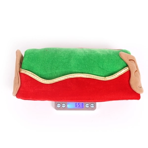 Détail montrant un bonnet de Noël en peluche rouge et vert de 65,1g sur une balance