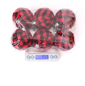 Detailed view of red and black buffalo plaid Christmas balls weighed on a digital scale