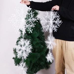 Detail of white 3D snowflake ornaments strand held by hand for Christmas decoration