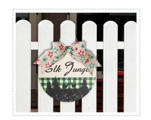 Close-up of wooden Christmas door sign with Elk Jungle text and a festive burlap bow