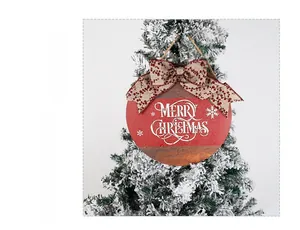 Close-up of wooden Merry Christmas door sign with burlap bow hanging on a snowy tree