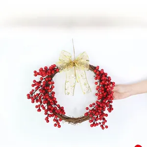Detail of Christmas wreath with red berries, natural vine base, and gold bow decoration