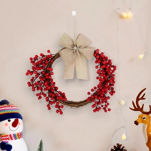 Detail of Christmas wreath with red berries and a large burlap bow on a wall