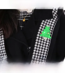 Détail d'une broche sapin de Noël lumineuse avec paillettes sur un revers de manteau