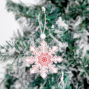 Flocon de neige de Noël en bois blanc avec motifs rouges festifs sur des branches enneigées