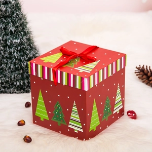 Detalle de caja de regalo de Navidad roja con motivos de árboles y cinta de seda