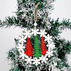 Hollow wooden Christmas snowflake pendant with red and green trees on a snowy branch