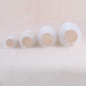 Detailed view of four round nylon cleaning brushes with natural wood base in various sizes