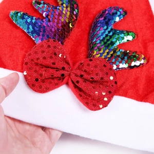 Dettaglio del cappello di Natale in peluche con corna di renna in paillettes e fiocco rosso