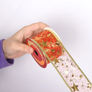 Detail of Christmas ribbon with gold stars and musical notes on a red cardboard spool