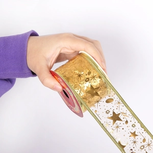 Macro detail of white Christmas ribbon with gold foil stars, notes, and green edges
