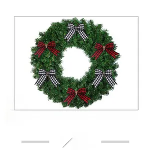 Close-up of artificial pine wreath decorated with classic red and black checkered bows
