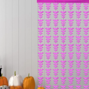 Close-up of pink bat tinsel curtain for Halloween party decor on white wall background