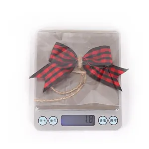 Detail view of a 1.8g red and black buffalo plaid Christmas bow with hemp rope on a scale