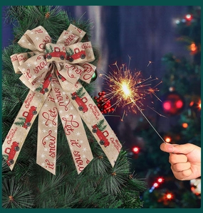 Close-up of beige linen Christmas bow with red truck print hanging on a festive tree branch