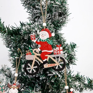 Wooden Christmas snowman riding bike ornament with xmas text hanging on snowy pine tree