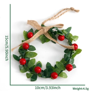 Mini Christmas wreath hanging with green leaves and red berries for festive tree decor