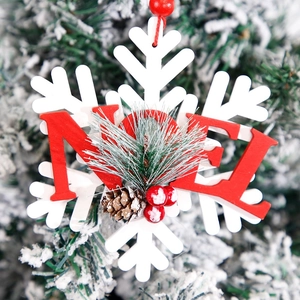Christmas wooden snowflake ornament with red NOEL letters and pine cones hanging on tree