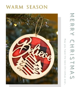 Macro detail of wooden Believe ornament with red buffalo plaid and laser-cut pine trees