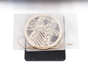 Detailed view of a circular wooden snowflake ornament with Believe text in packaging