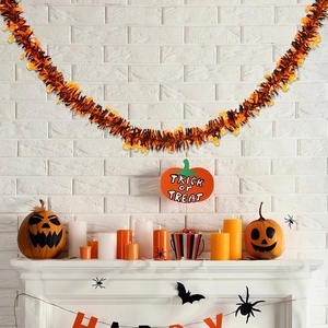 Close-up of Halloween orange tinsel garland with pumpkin charms on a fireplace mantle
