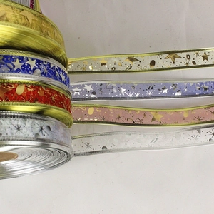 Close-up of 2.5cm Christmas ribbons with gold edges and festive star patterns for gift wrapping
