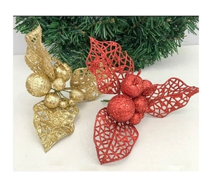 Close-up of glittered Christmas tree ornaments with red and gold hollow leaves and berries