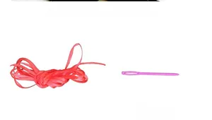 Detail of red ribbon roll and pink plastic threading needle for Christmas party banners