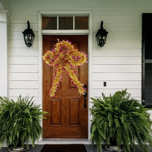 Close-up of sparkling gold and pink Christmas tinsel bow hanging on a rustic wooden door