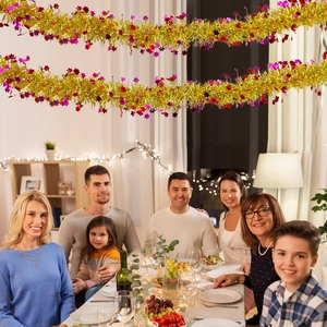 Macro detail of festive golden Christmas garland with red stars in a warm family dinner setting