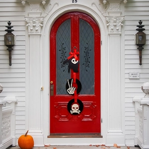 Black wooden Halloween door hanger with skull and cat motifs on a red arched door