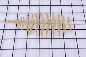 Detailed view of artificial gold glitter fern leaf for Christmas tree and party decor