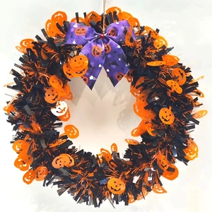 Close-up of Halloween tinsel wreath with pumpkin sequins and purple printed bow detail