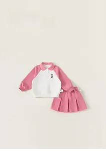 Detail of pink and white color-block polo shirt with small bear embroidery and pleated skirt