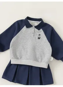 Detail of navy blue polo sweatshirt with bear embroidery and pleated skirt for girls