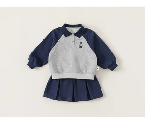 Detail of kids navy polo shirt with bear embroidery and matching pleated skirt