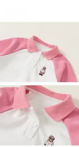 Close-up of pink and white polo shirt collar with fine bear embroidery detail